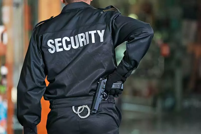 Security Man Standing Indoors Pulling Gun in Emergency Situation