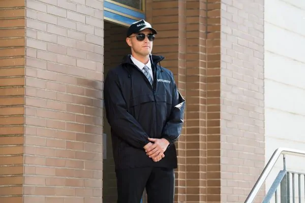 Unarmed security guard standing at the building entrance.