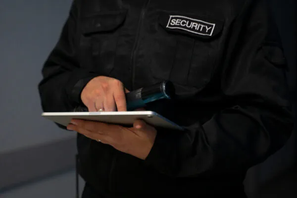 Security guard monitoring security system on tablet