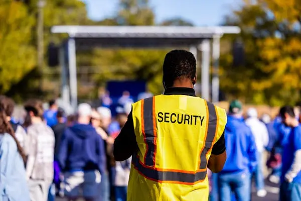 Mall security guard wearing a yellow high-visibility vest while watching over a crowded outdoor event