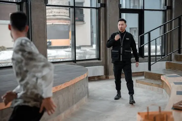 Mall security guard in a black uniform speaking to another person inside a modern building
