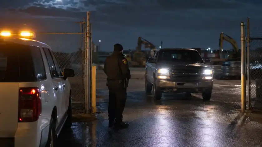 Security officer controlling access at a Houston construction site gate at night