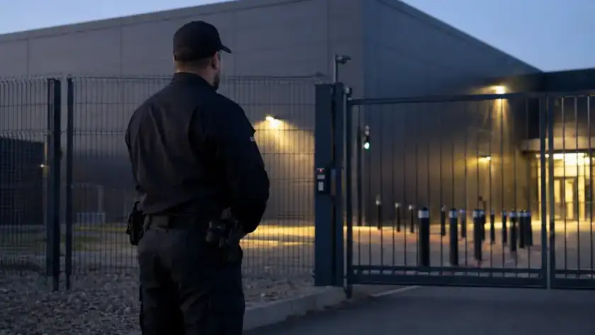 Security officer at the gated entrance of a Houston data center at dusk