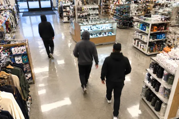 Three people moving together through a store aisle in an organized retail crime pattern