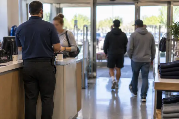 Store employee turned away as two people pass toward the sales floor