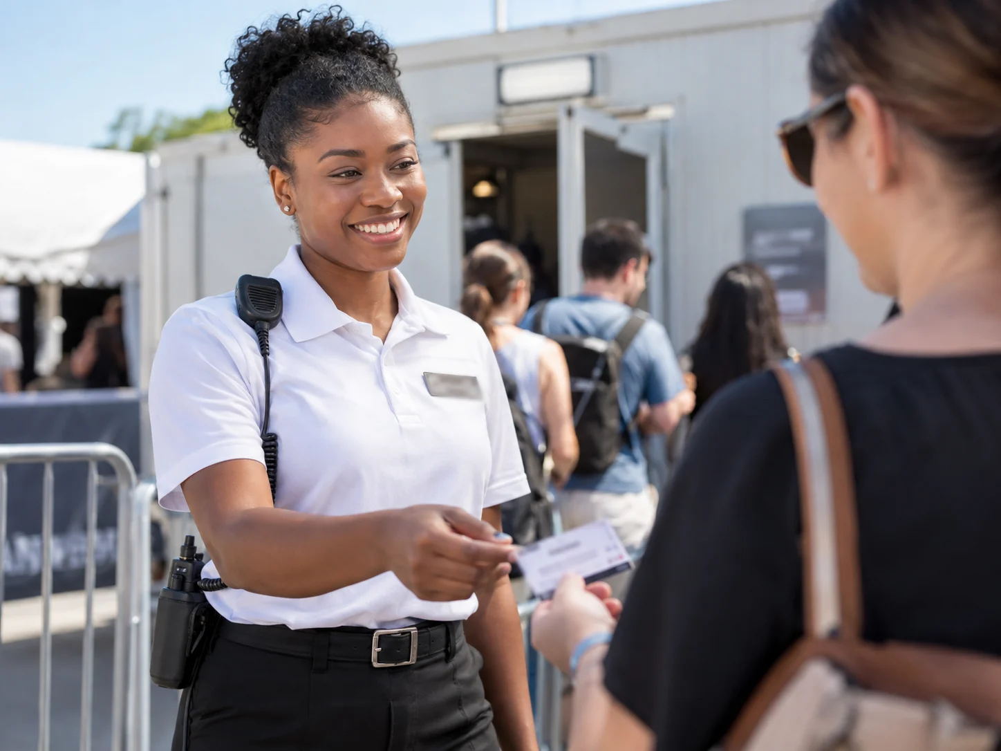 Smiling female guard checking visitor passes at a temporary building entrance